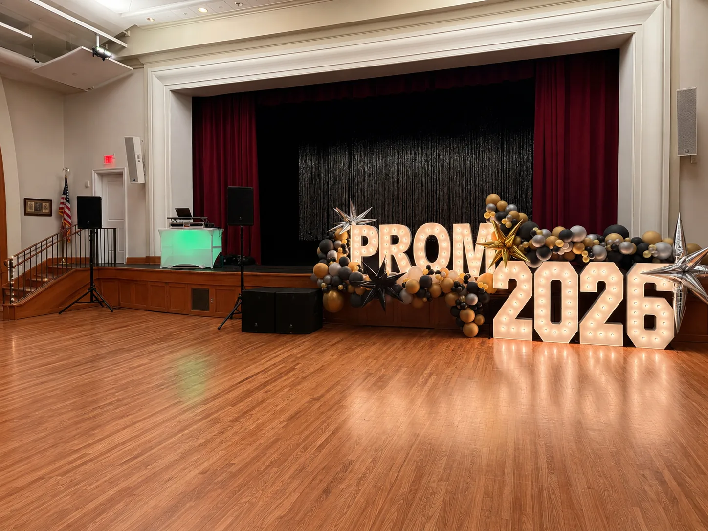 Prom 2026 stage with DJ setup, subwoofers and PA speakers in a school auditorium