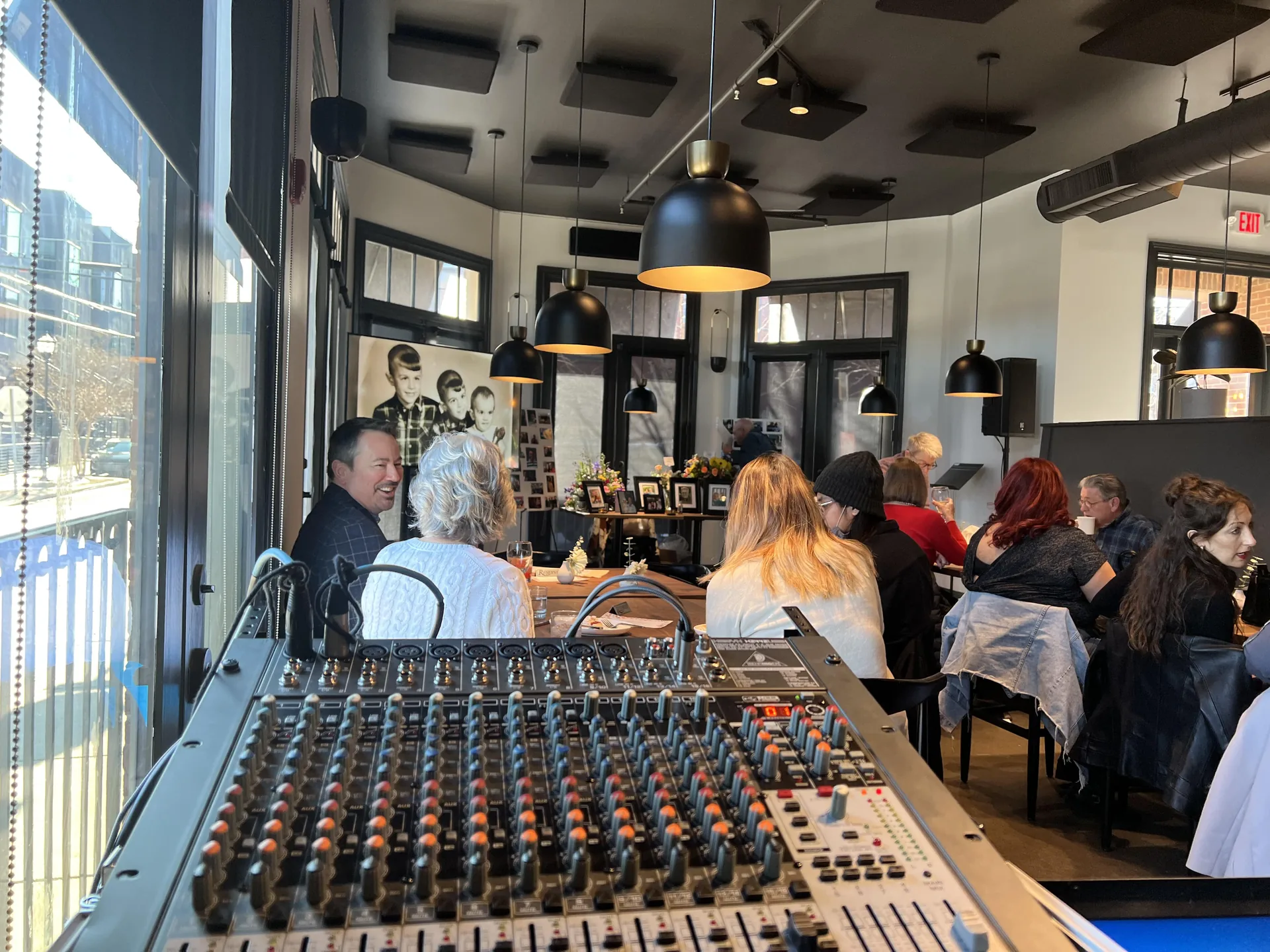 View from the audio mixer at a busy restaurant event, showcasing the dining crowd and modern interior