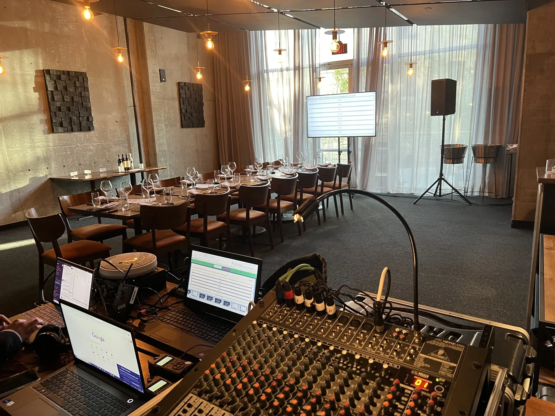 Restaurant event production setup with an audio mixing console, PA speaker and slideshow on a large TV display