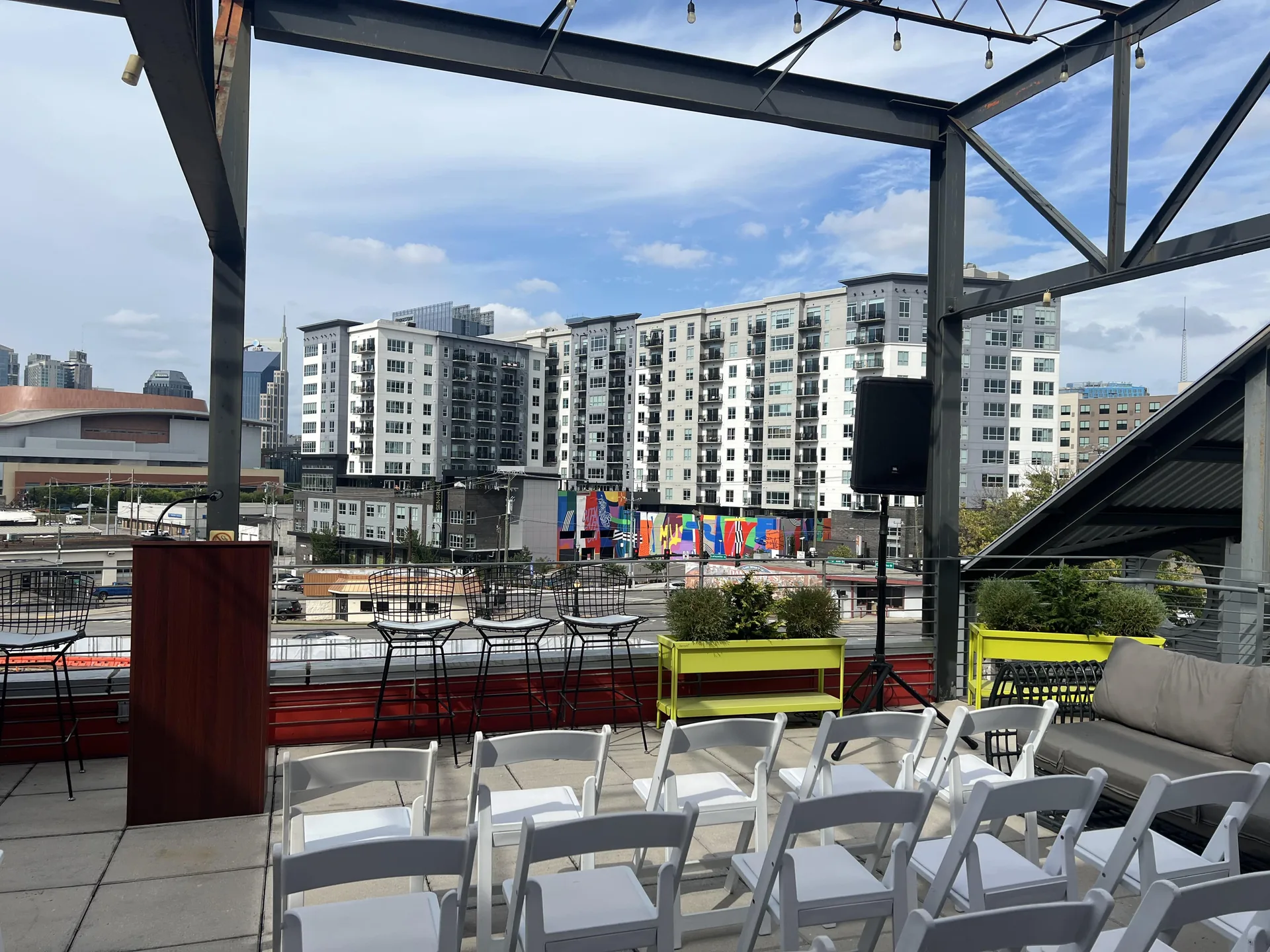 Rooftop event setup with a podium, PA speaker and seating area overlooking the city