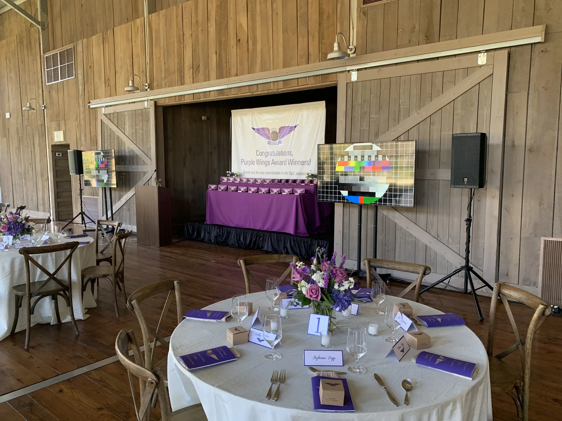 Rustic awards ceremony with a TV display, PA speakers and purple event décor
