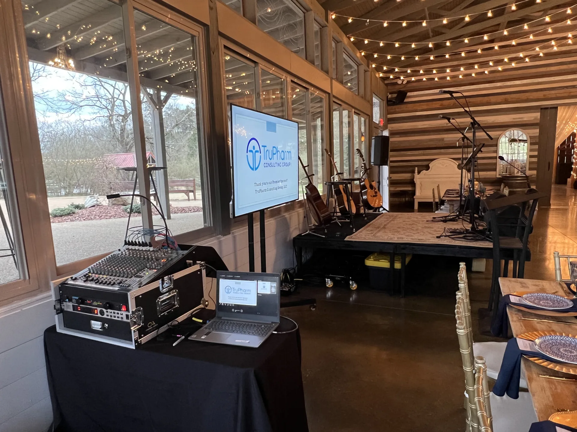 Rustic venue with a TruPharm Consulting presentation on a TV display and PA audio equipment