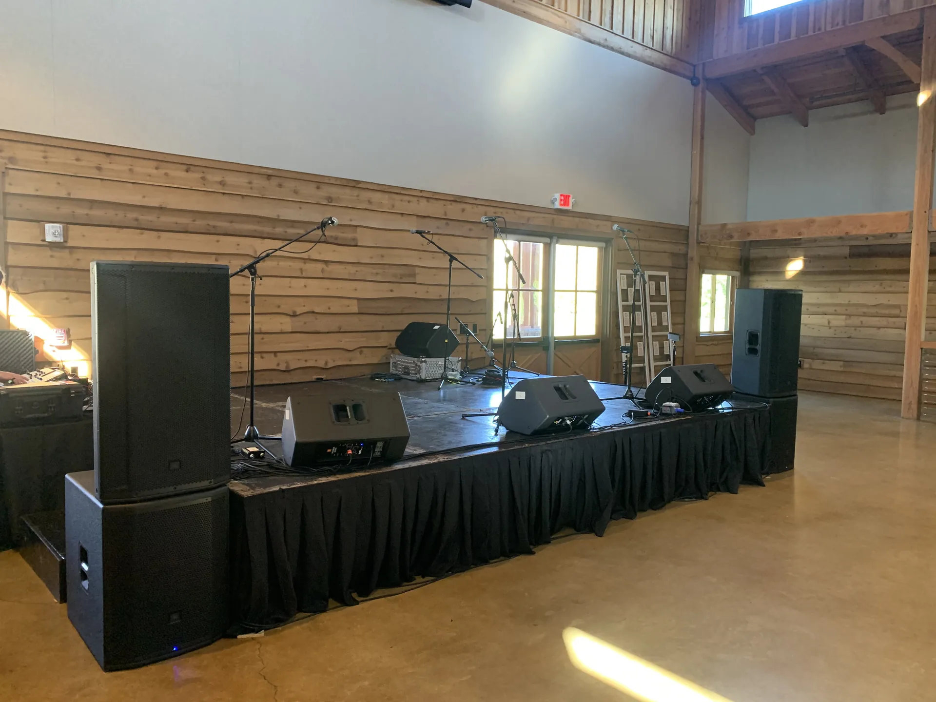 Rustic indoor event space with professional audio equipment set up on a wooden stage
