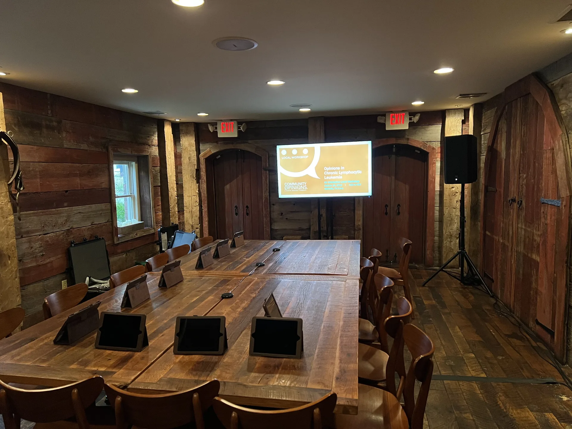 Rustic presentation room with a TV display, PA audio equipment and a long table