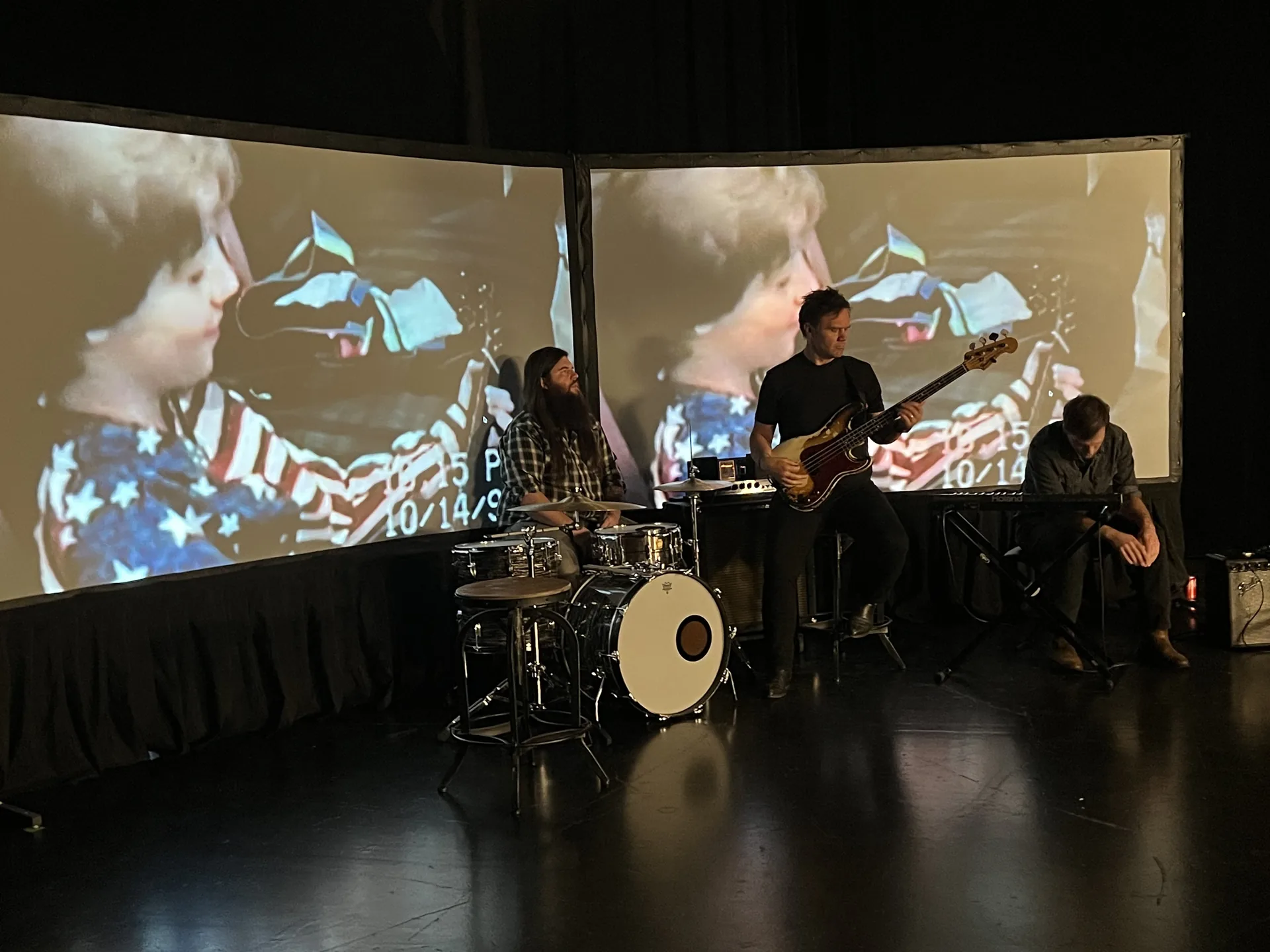 Singer performing on stage with a band and projected visuals in the background