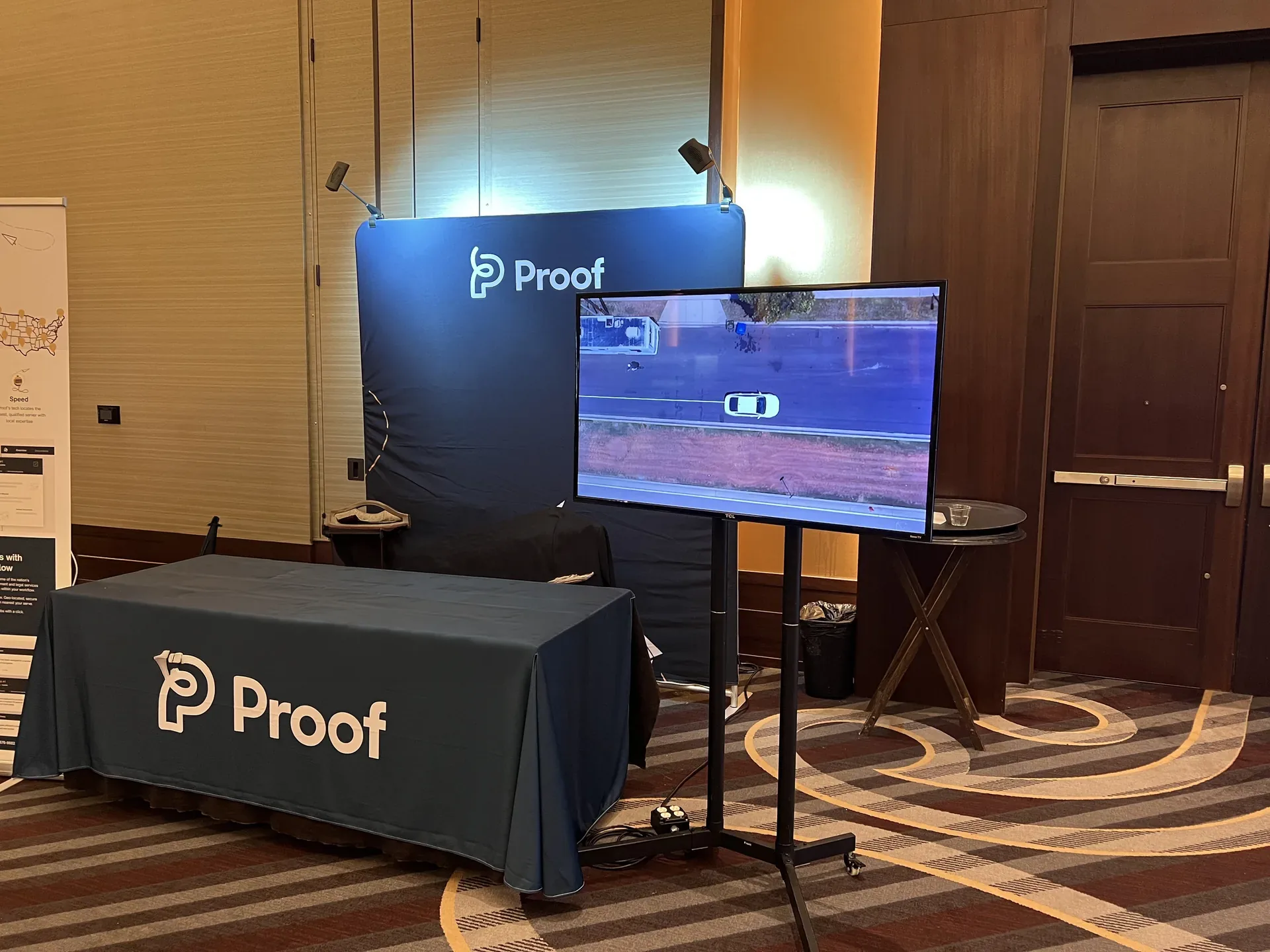 Tech company booth at a trade show featuring a large display screen