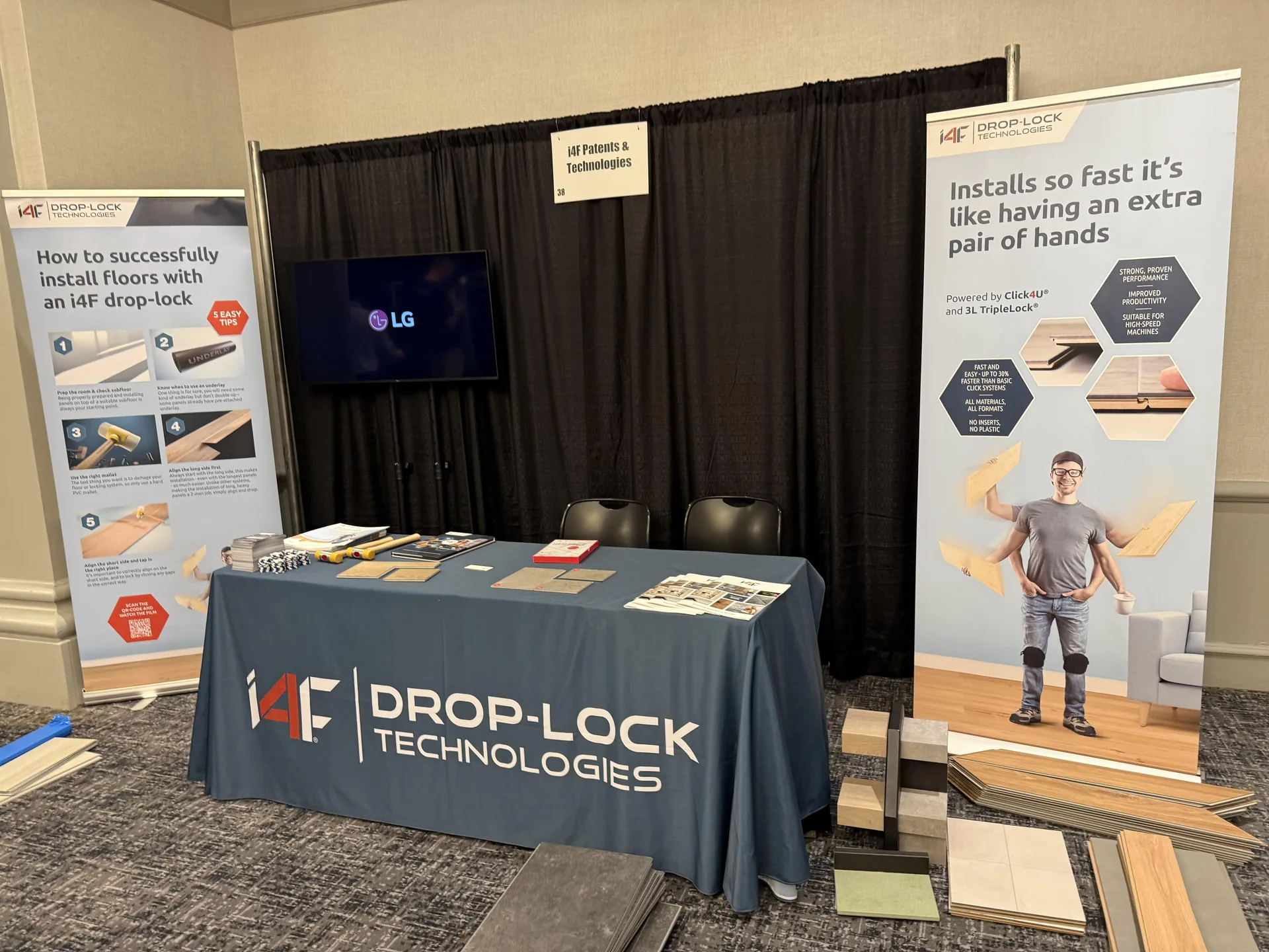 Trade show booth display for Drop-Lock Technologies featuring LG screen, banners, and flooring samples