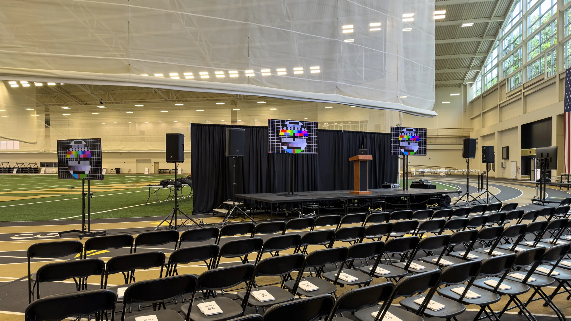 Three TV displays on floor stands with PA audio equipment around a stage for a Vanderbilt University event in Nashville