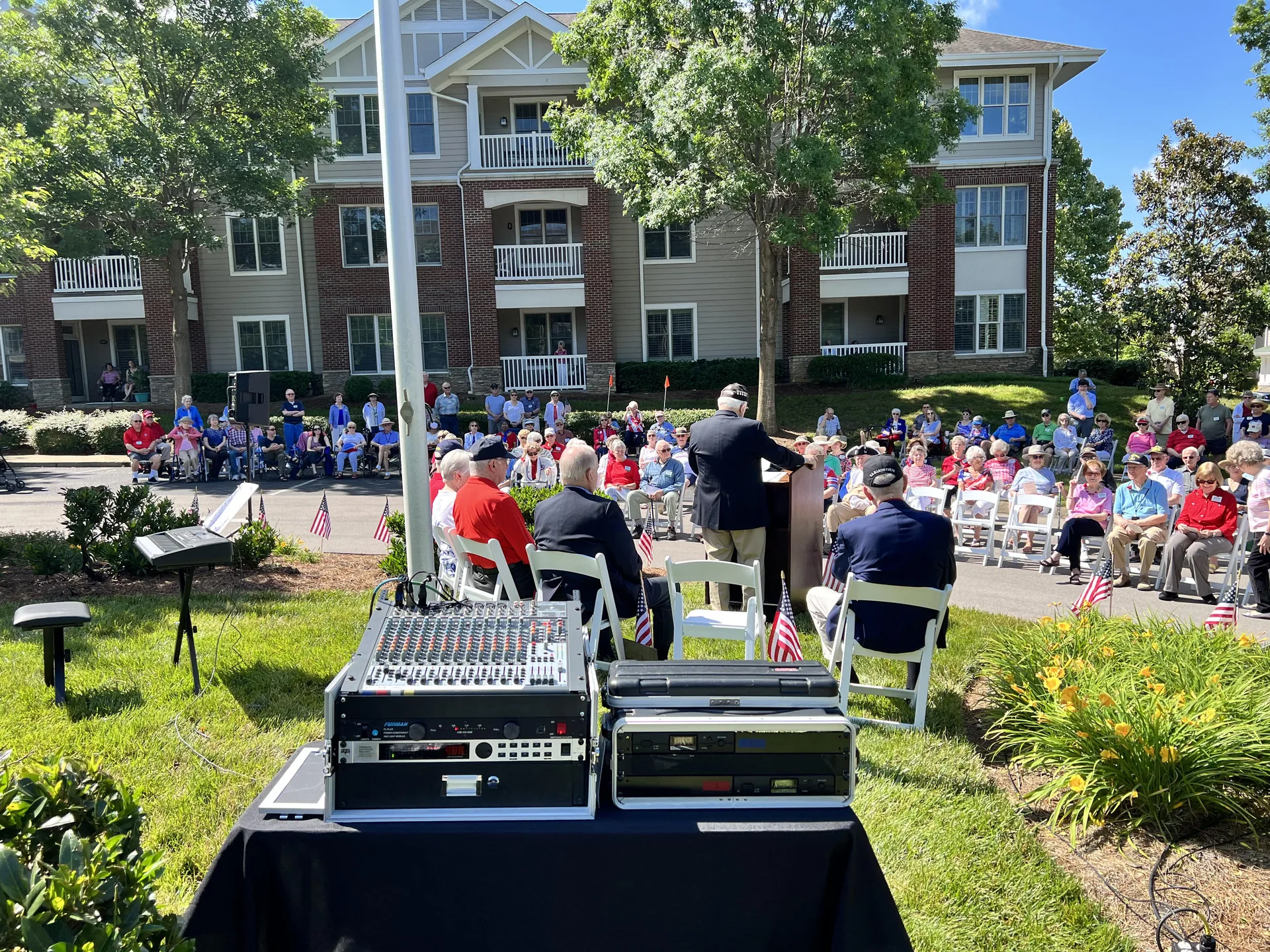 View from the audio mixing position at an outdoor veterans event while a presenter addresses the audience