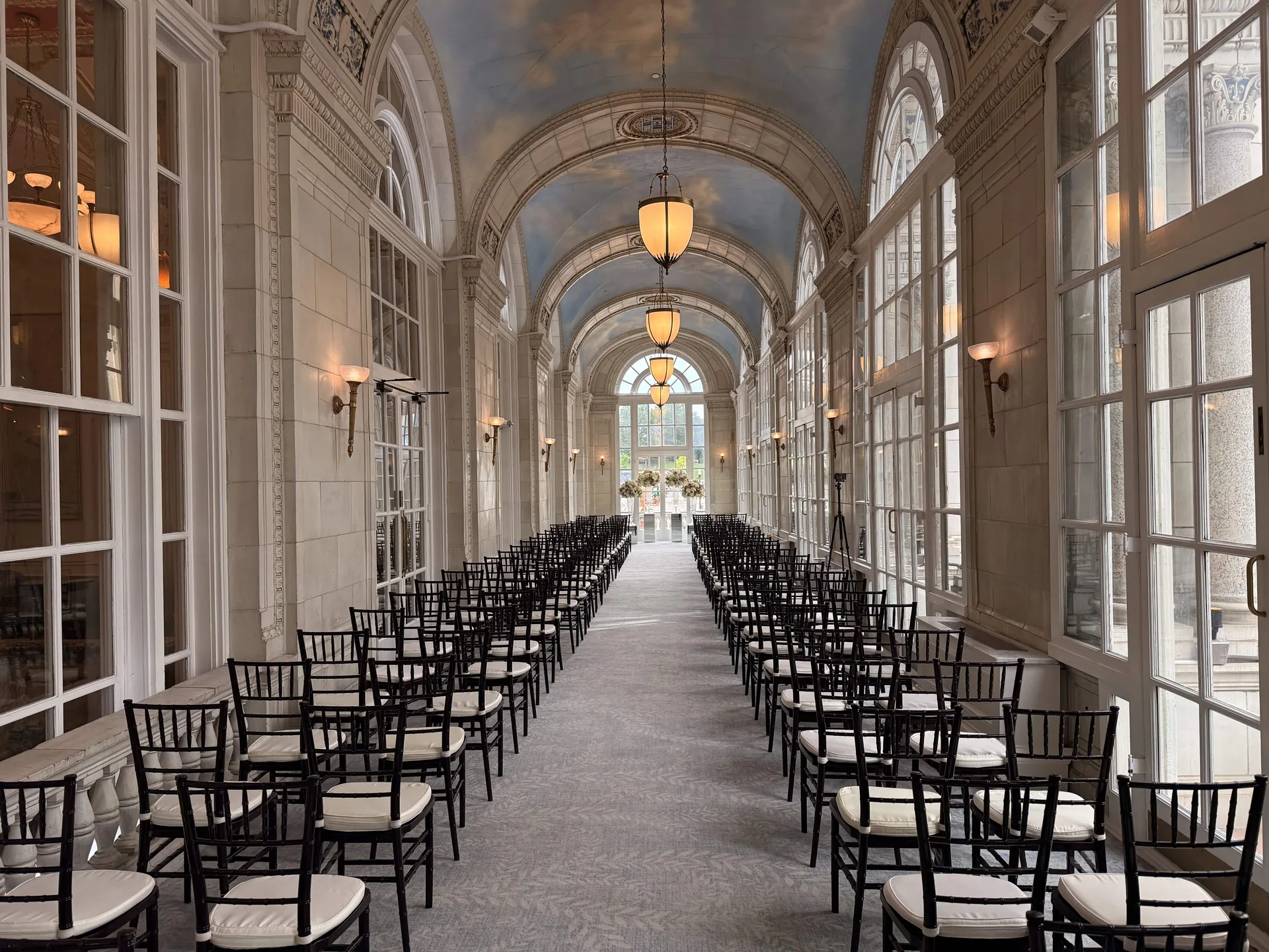 Wedding ceremony aisle with rows of chairs and event audio equipment in a naturally lit venue