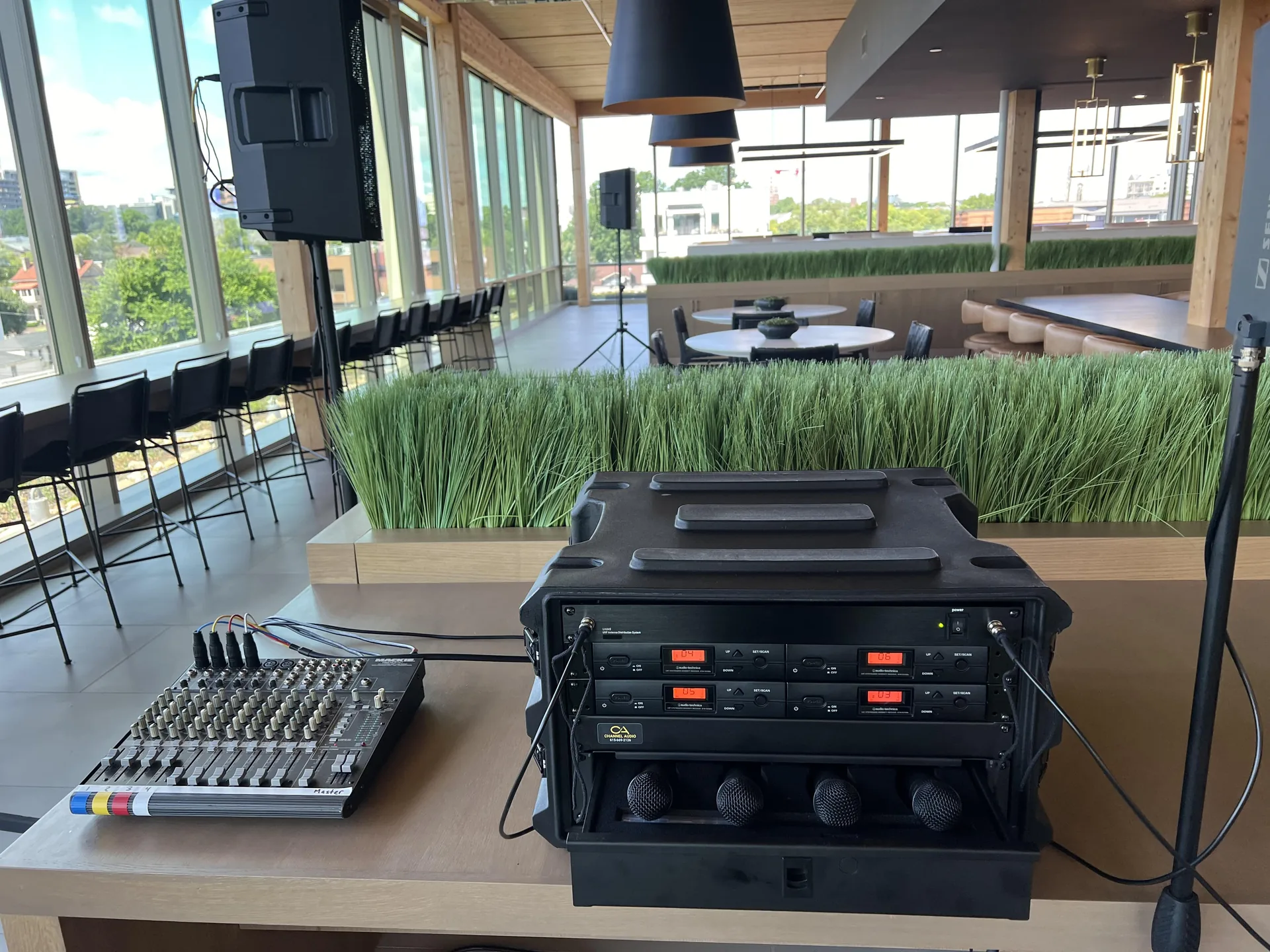 Compact wireless microphone system and audio mixer setup on a table at a modern event venue